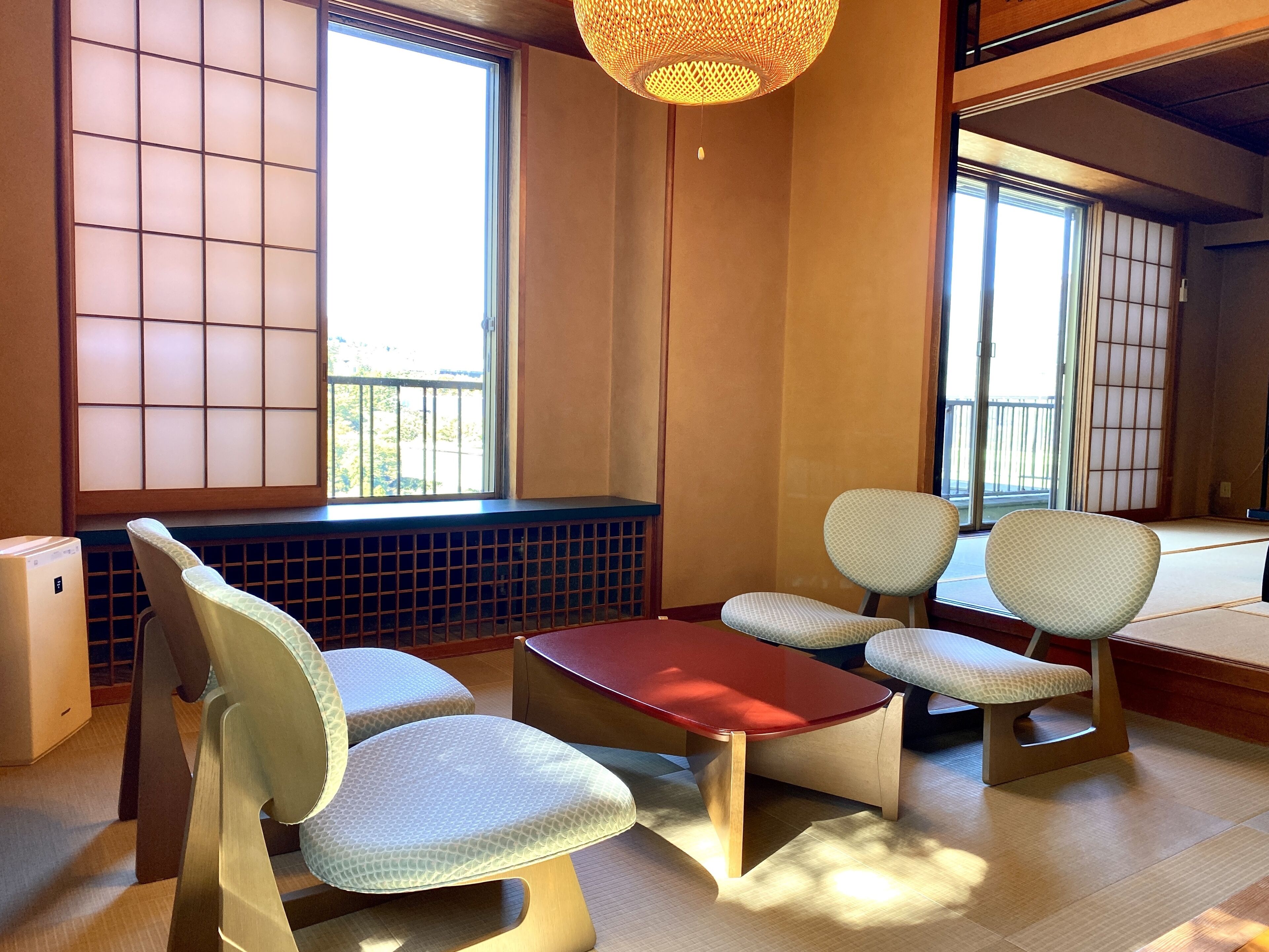 A traditional Japanese-style room with tatami flooring, a low table, and two cushioned chairs.