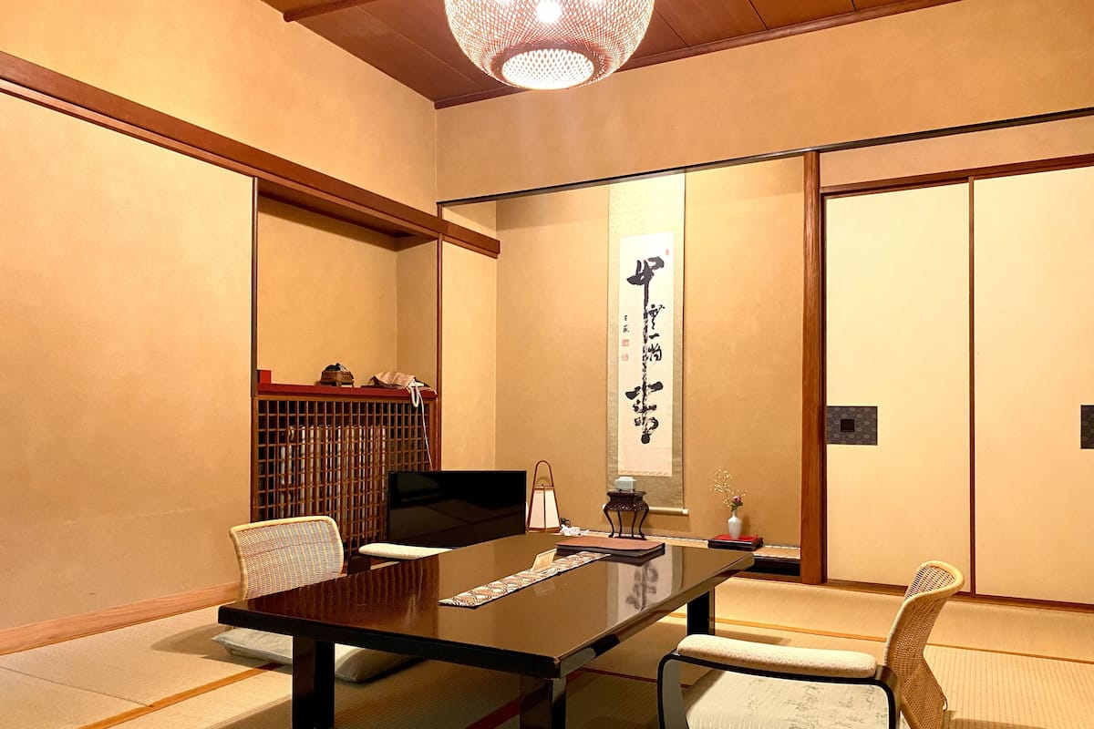 A traditional Japanese-style room with tatami flooring, a low table, and chairs.