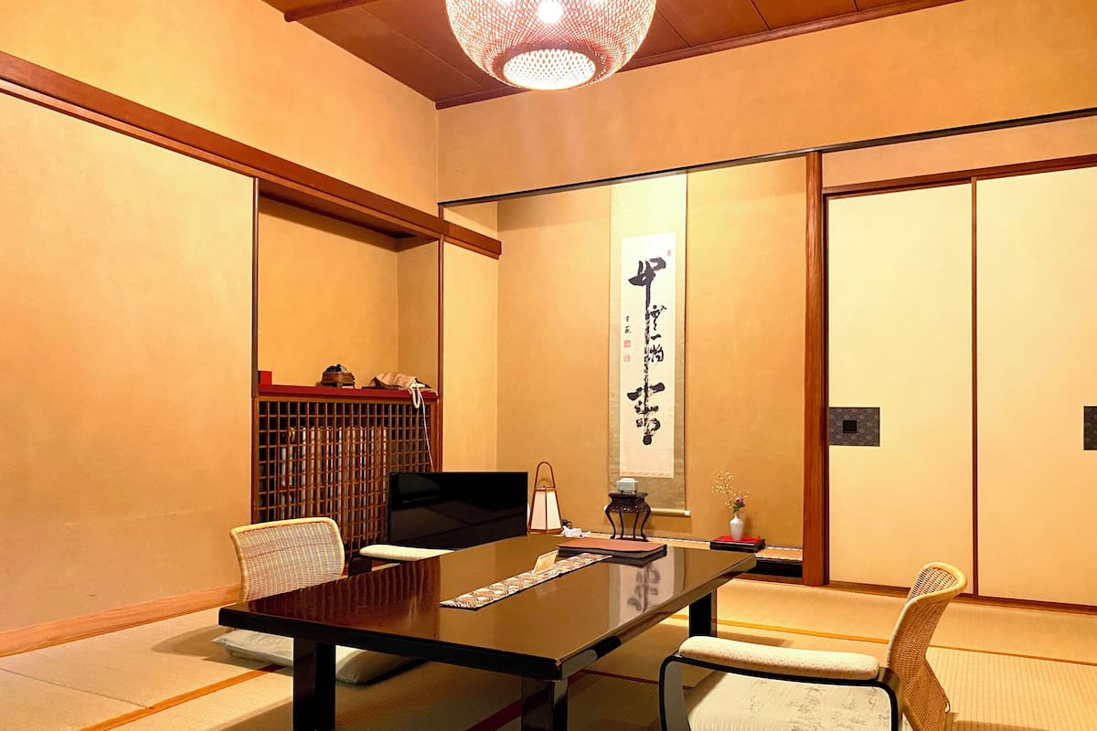 A traditional Japanese-style room with tatami flooring, a low table, and chairs.