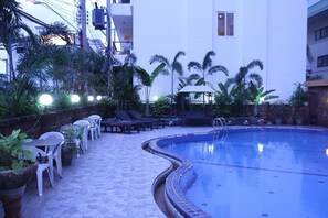 Un espace piscine agrémenté de chaises longues, de plantes en pot et d’un chemin pavé.
