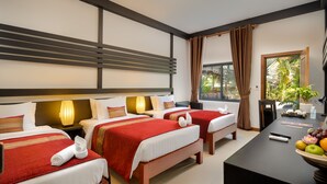 Quarto de hotel com duas camas, uma secretária com uma travessa de fruta e vista para o verde lá fora.
