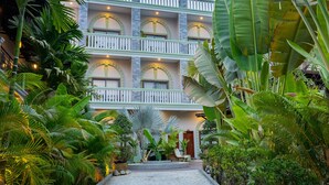 Um hotel com vários andares e varandas, rodeado por vegetação tropical exuberante.