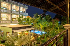 A hotel with a pool, lush greenery, and a covered outdoor area at night. - Reveal Angkor Hotel (Siem Reap)