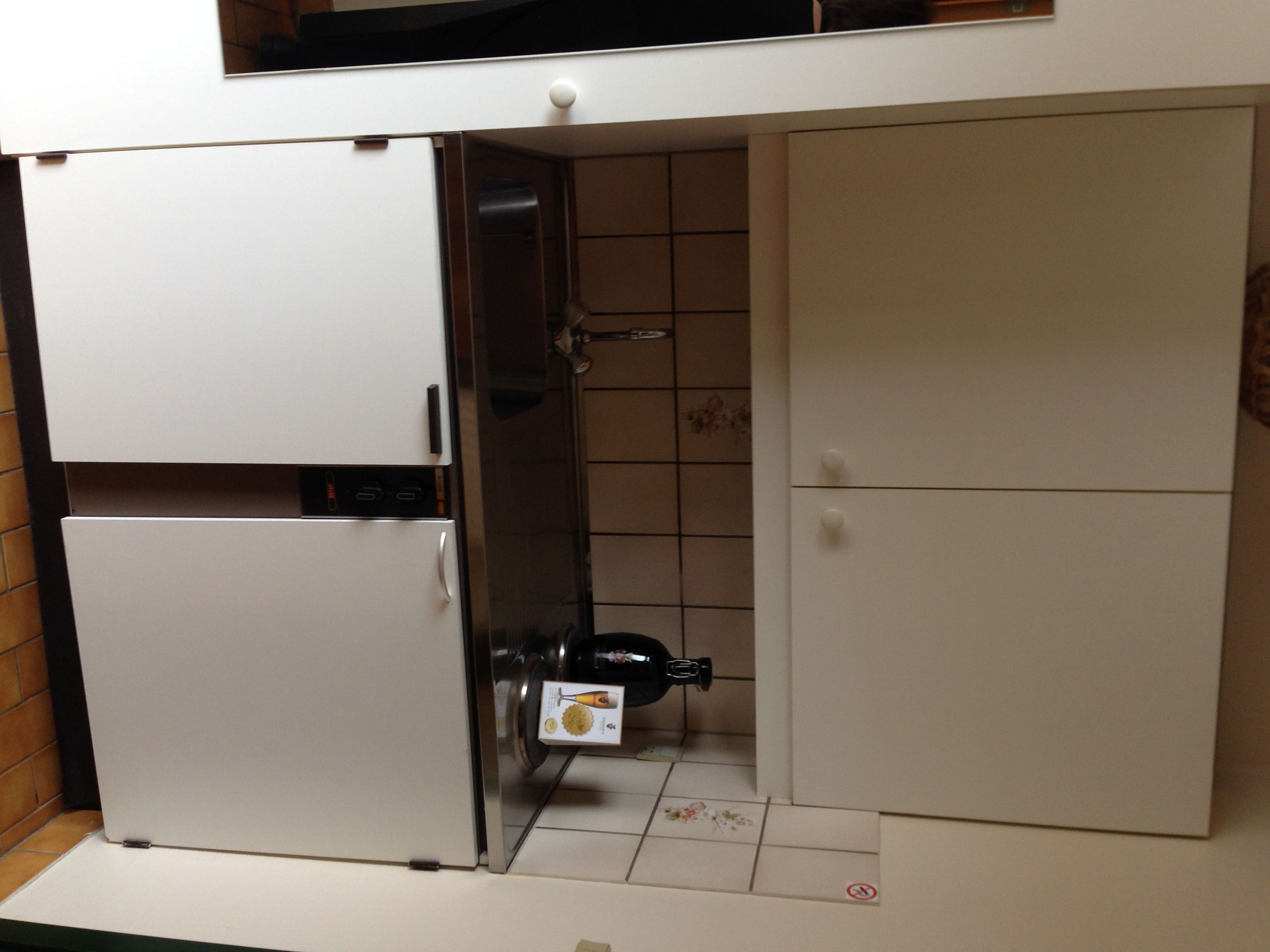 A compact kitchen with a built-in refrigerator, a microwave, and a sink.