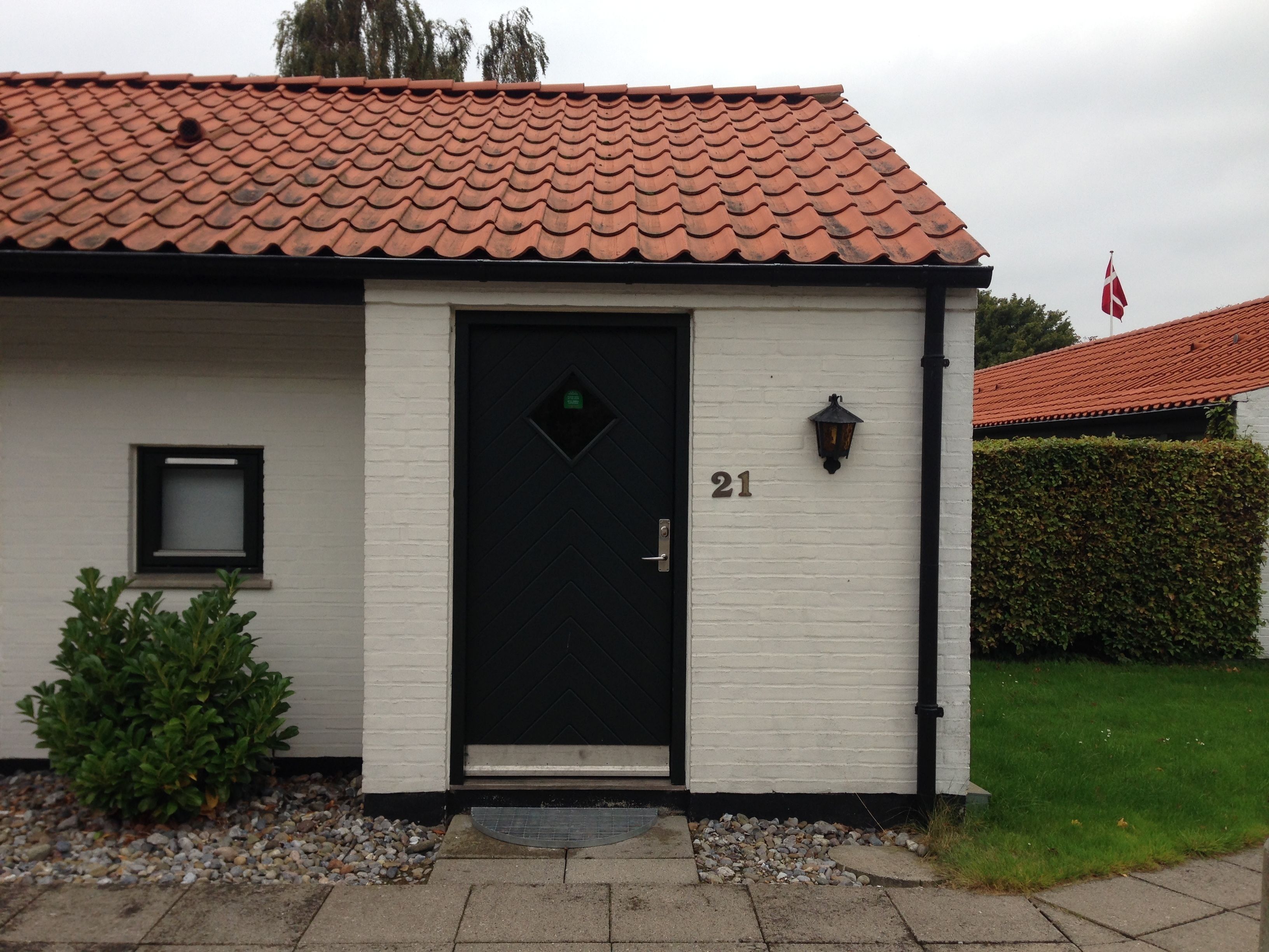 A building with a black door, numbered 21, a small window, and a flag.