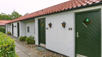 A row of white buildings with red-tiled roofs, numbered 28 and 29, featuring green doors and small windows.