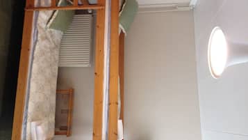 A room with a wooden ceiling structure, a window with blinds, and a wall-mounted light fixture.
