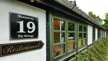 A building with a sign indicating 'Skansevej 19 The Cottage' and a 'Restaurant' sign below it.