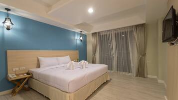 A hotel room with a large bed, a wooden headboard, a bedside table with a phone, and a TV mounted on the wall.