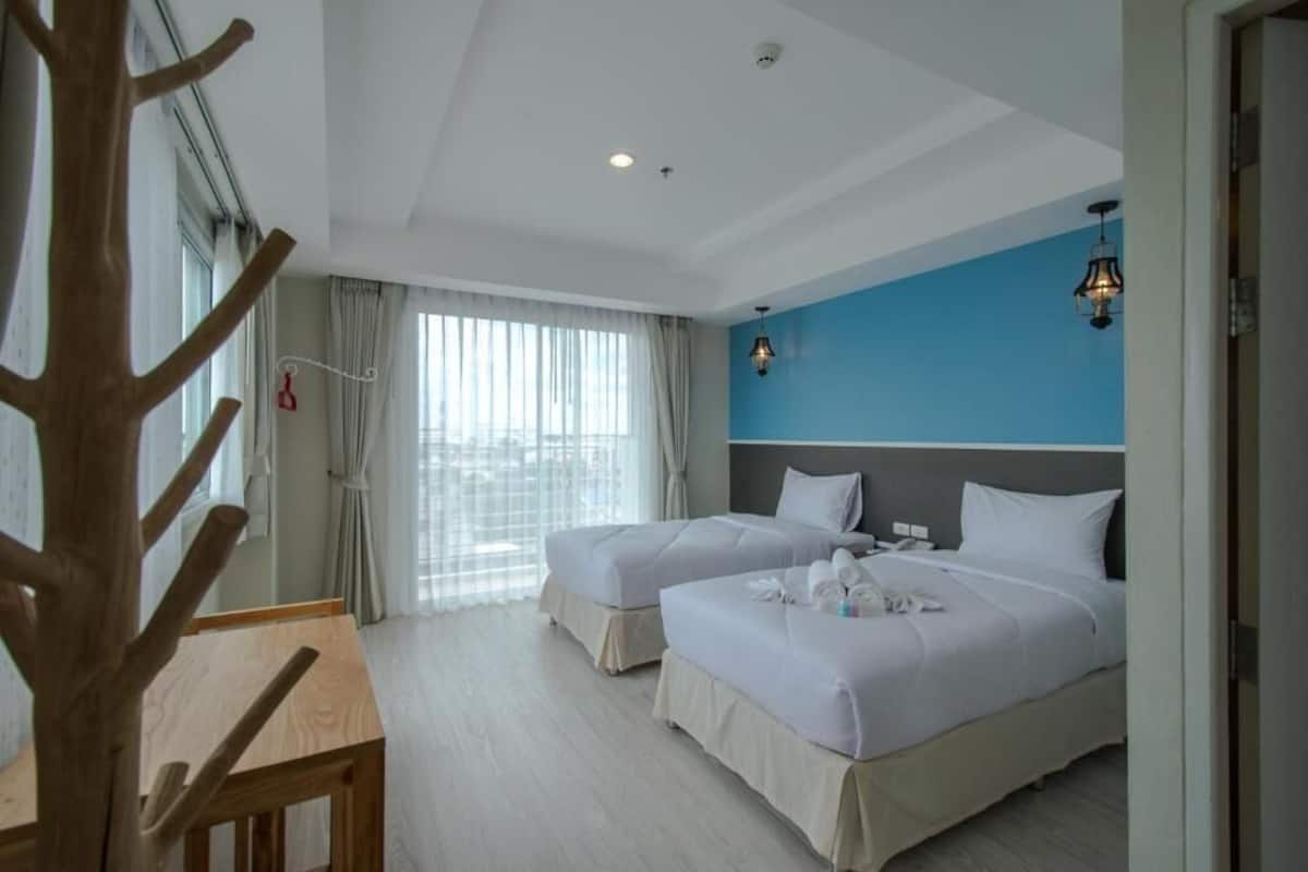 Une chambre d’hôtel avec deux lits, une table en bois et une vue sur l’extérieur.
