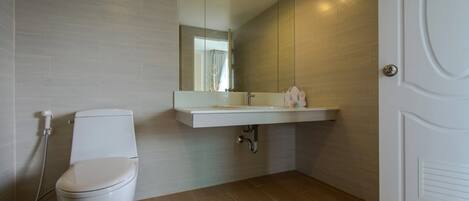 Ein modernes Badezimmer mit Toilette, Waschbecken und Spiegel.