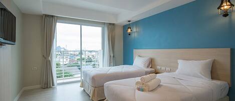 A hotel room with two beds, a large window, and a view of the city.