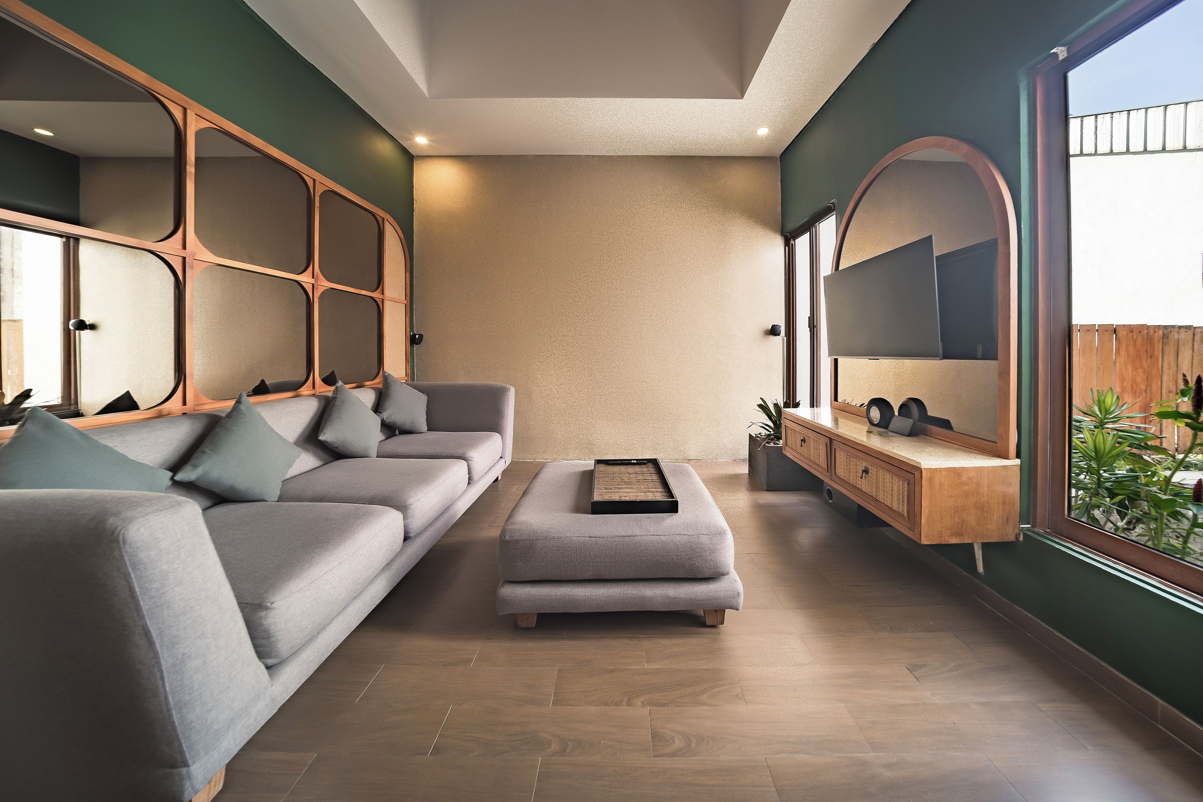 A modern living room with a grey sofa, a small ottoman, and a wooden console table with a mirror.