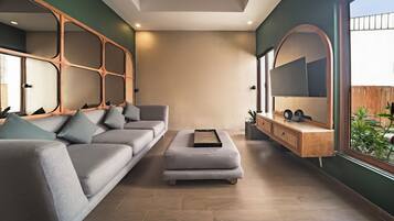 A modern living room with a grey sofa, a small ottoman, and a wooden console table with a mirror.