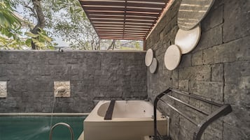 Zona de spa con pared de piedra, jacuzzi y piscina.