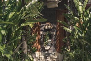A stone archway with a wooden door, surrounded by lush greenery. - Ini Vie Villa Seminyak by Ini Vie Hospitality (Legian)