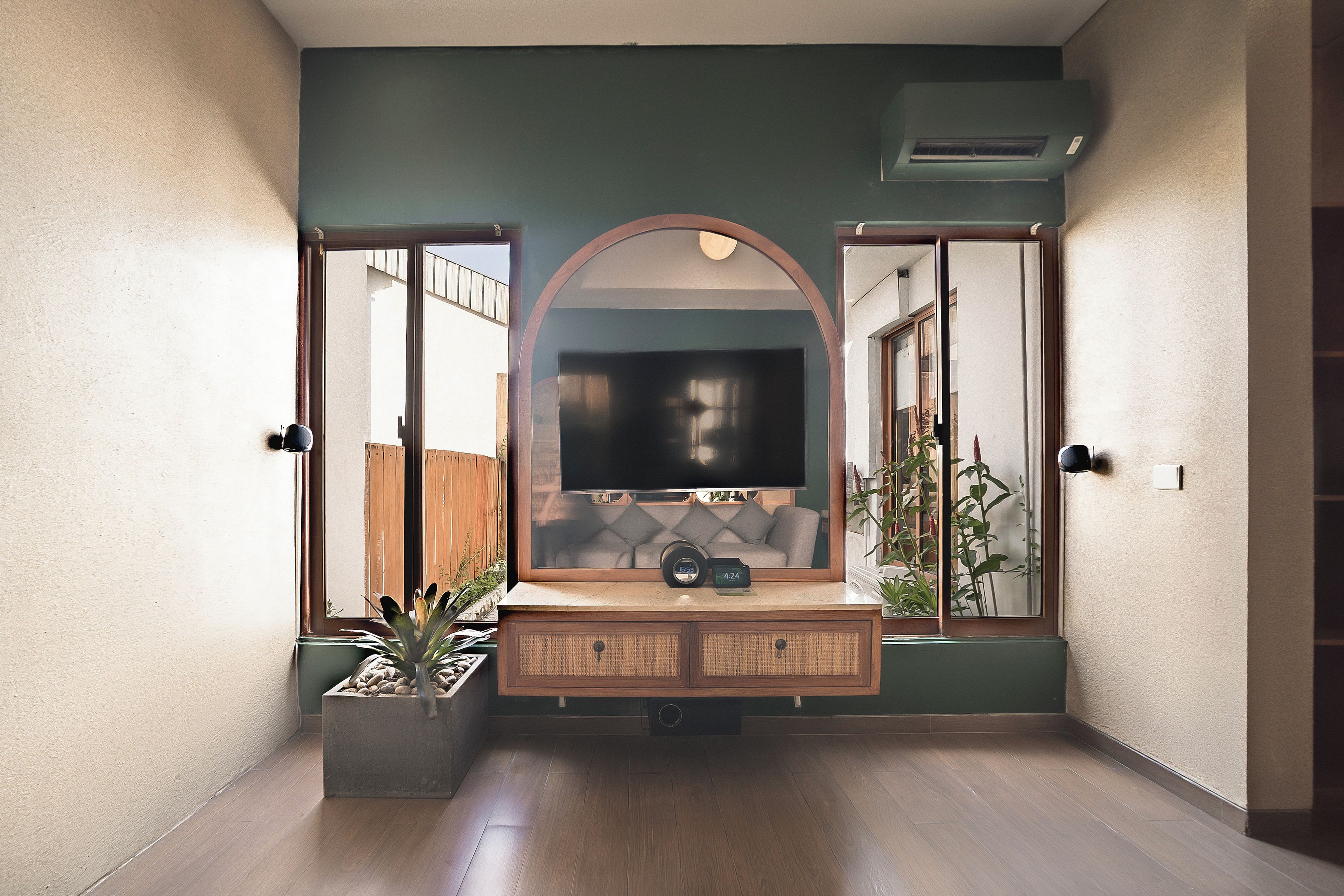 A hallway with a built-in entertainment unit featuring a flat-screen TV, a clock, and a small plant.