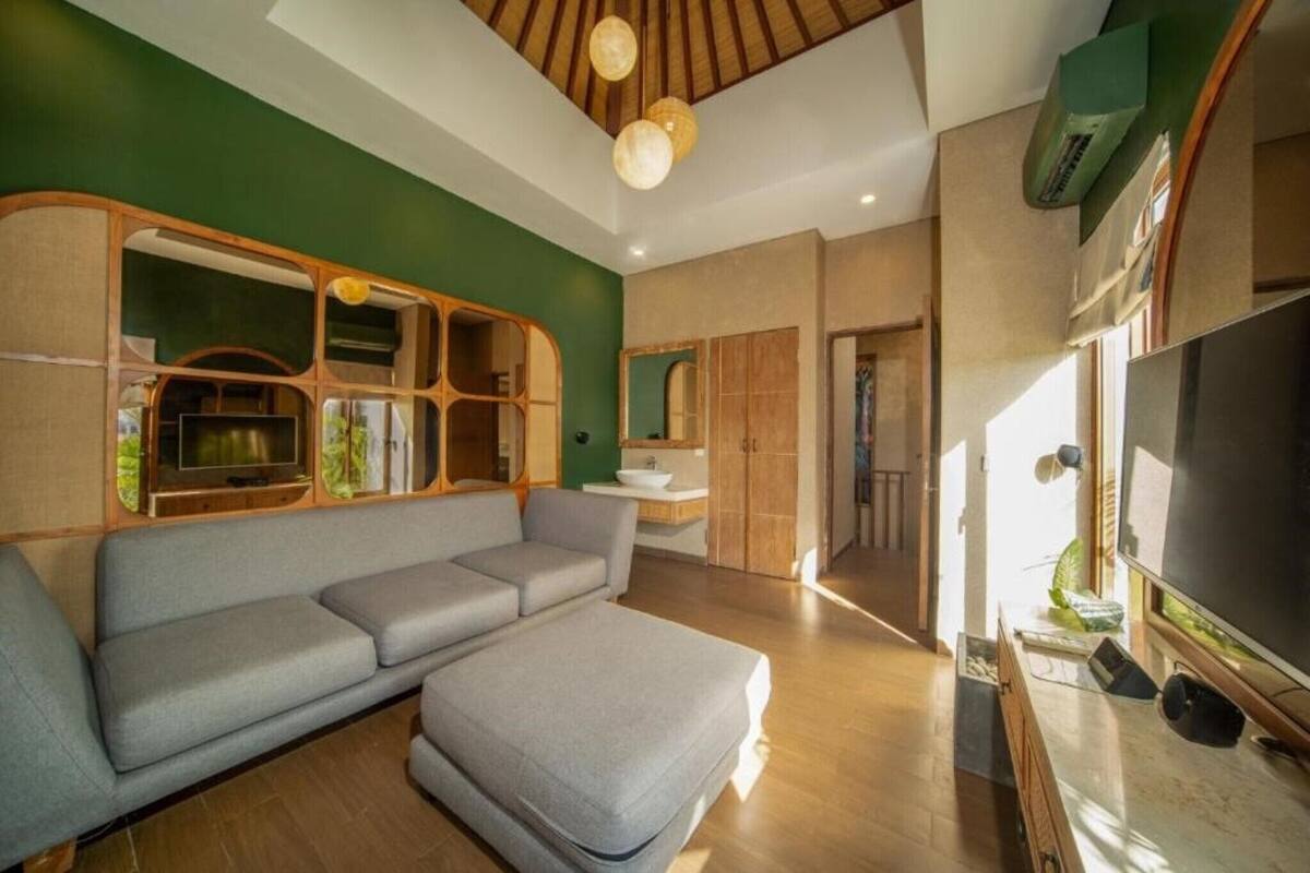 A modern living room with a sectional sofa, wooden built-in shelves, a television, and a large window.