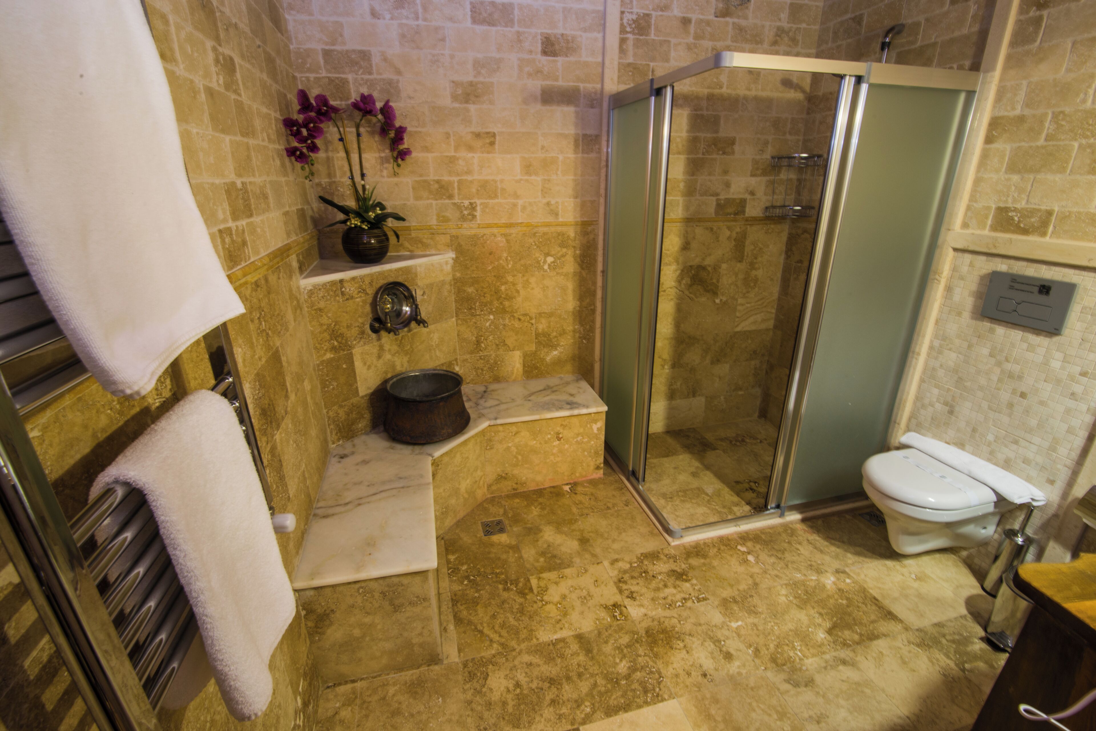 Un baño con cabina de ducha de vidrio, inodoro, lavabo y toallero.