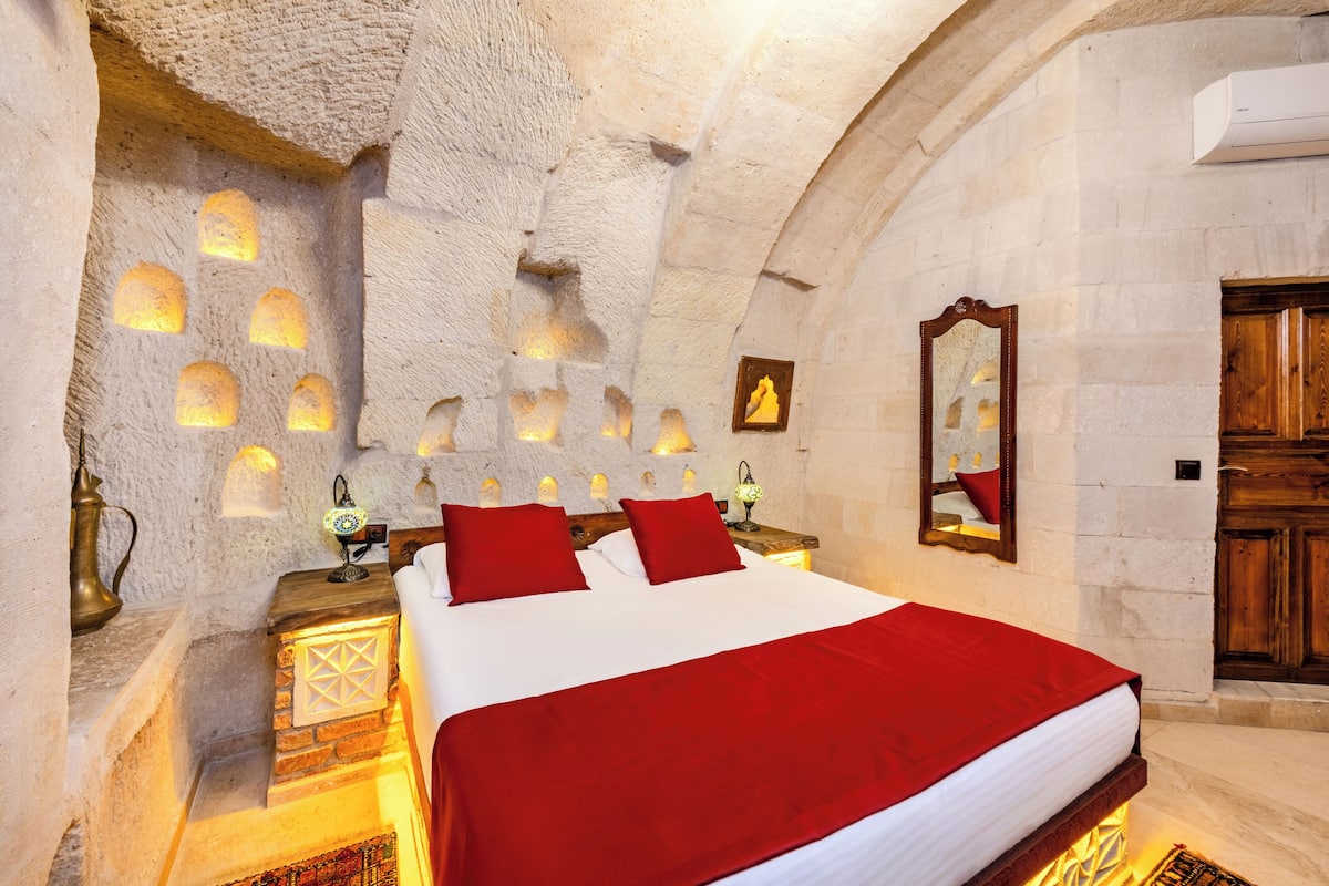 A room with a bed, stone walls, and a wooden door.