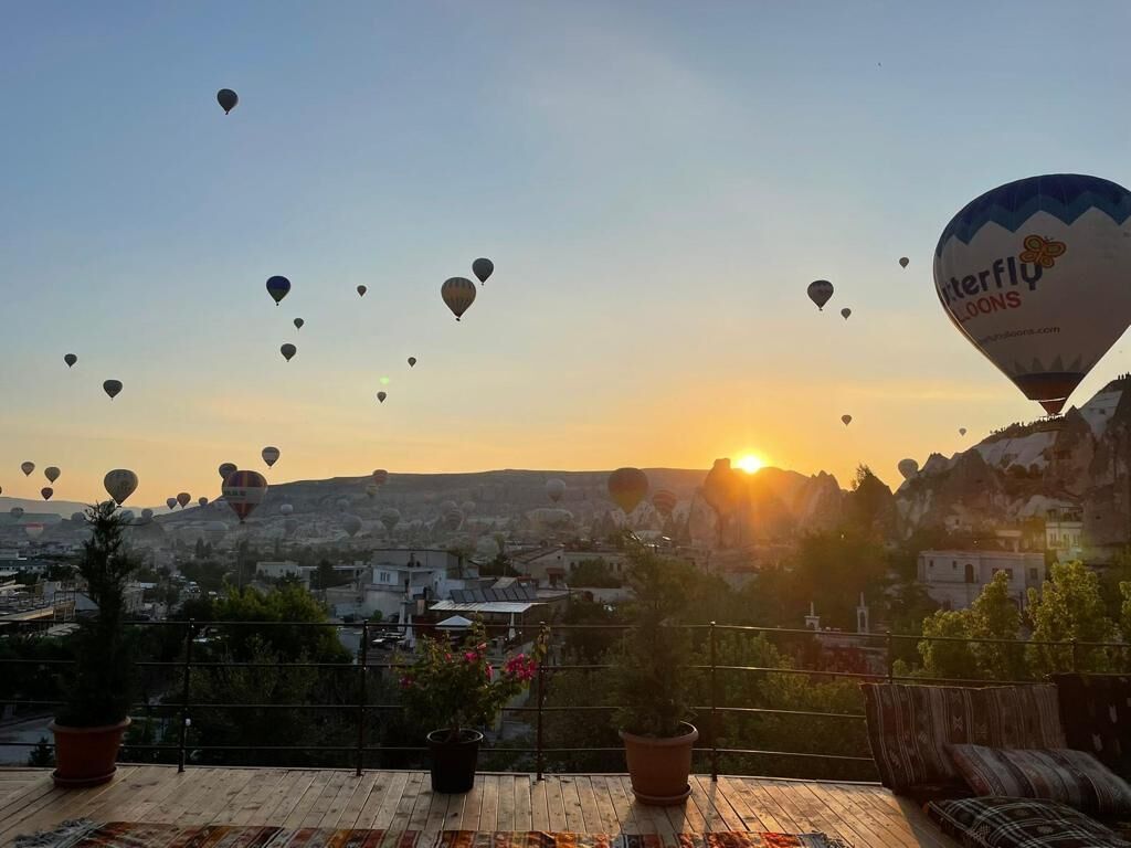 A sunset view with hot air balloons, a wooden deck, and potted plants.