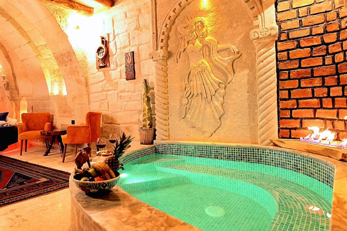 A spa room with a stone wall, a mural, a small pool, and seating areas.
