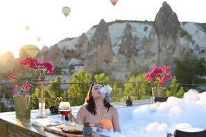A person in a bathtub with a mountainous landscape in the background. - Historical Goreme House (Nevsehir)