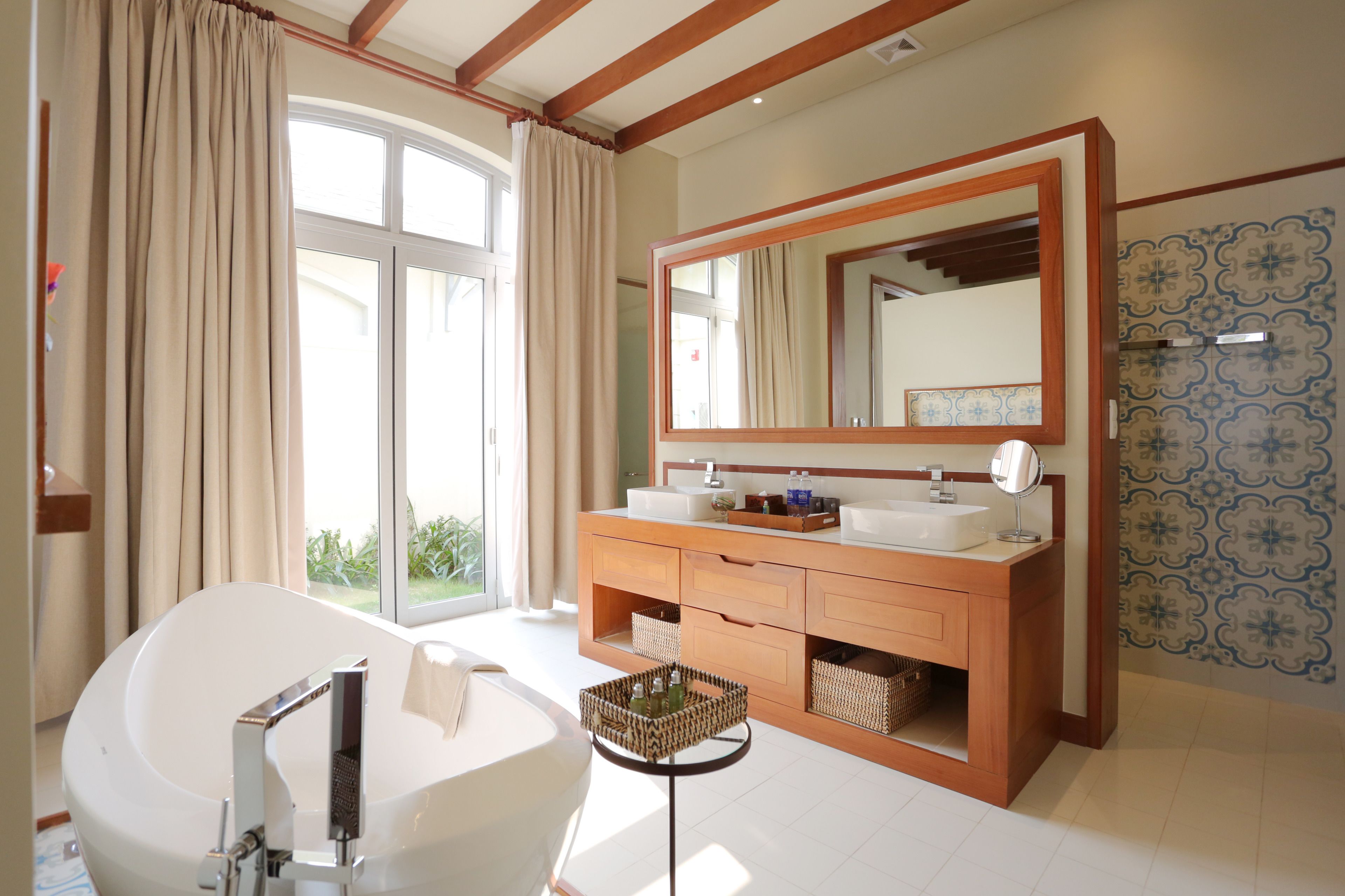 A modern bathroom with a freestanding bathtub, a large mirror, and a wooden vanity.