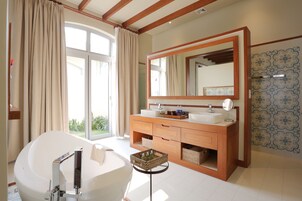 Un baño moderno con una bañera independiente, un espejo grande y un tocador de madera.