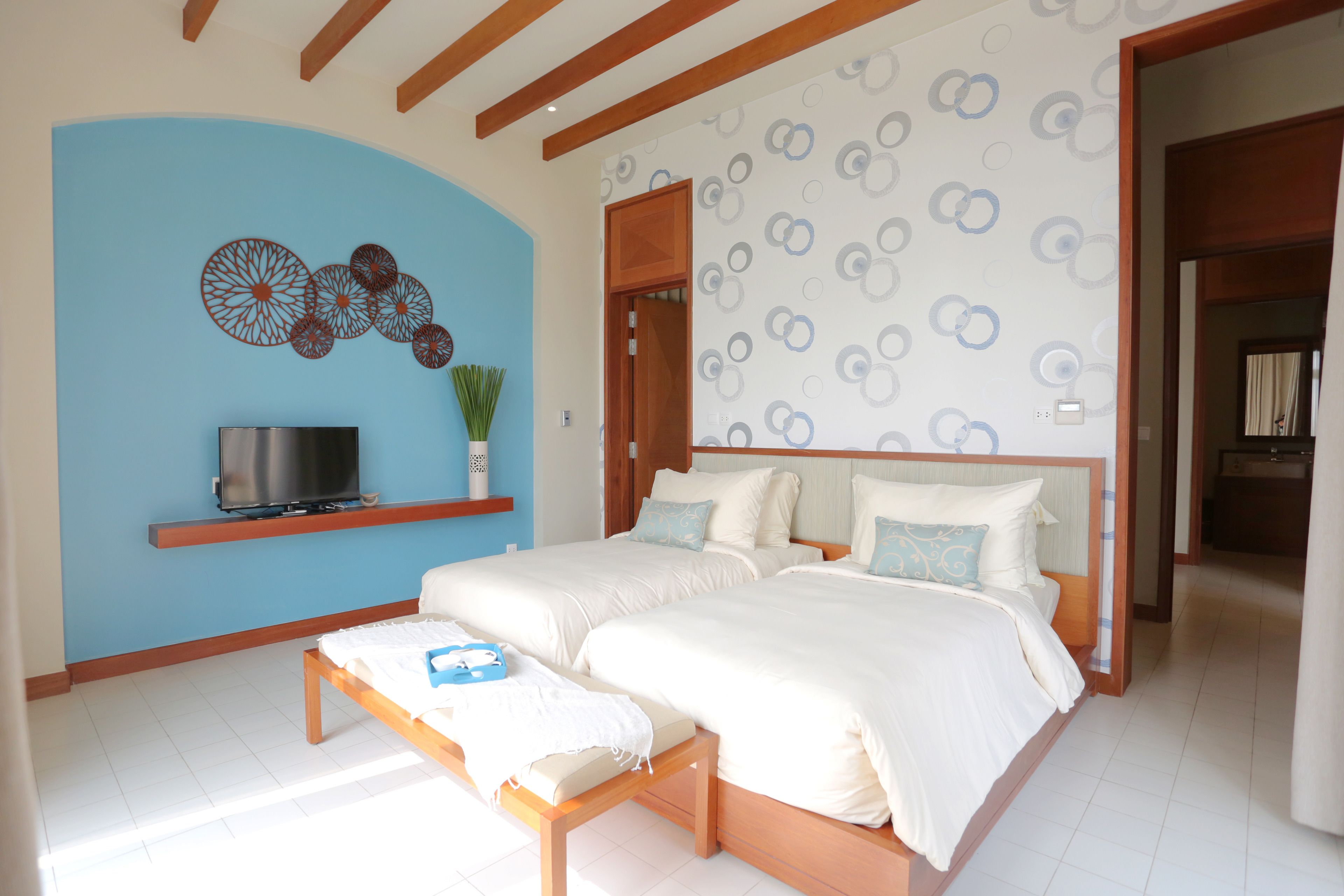 A bedroom with a large bed, a TV on a shelf, and a blue accent wall.