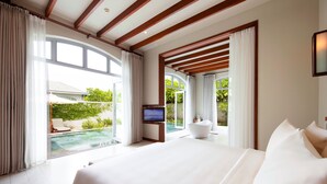 A modern hotel room with a large bed, a TV, and a view of a swimming pool and greenery. - FLC Luxury Resort Samson (Sam Son)