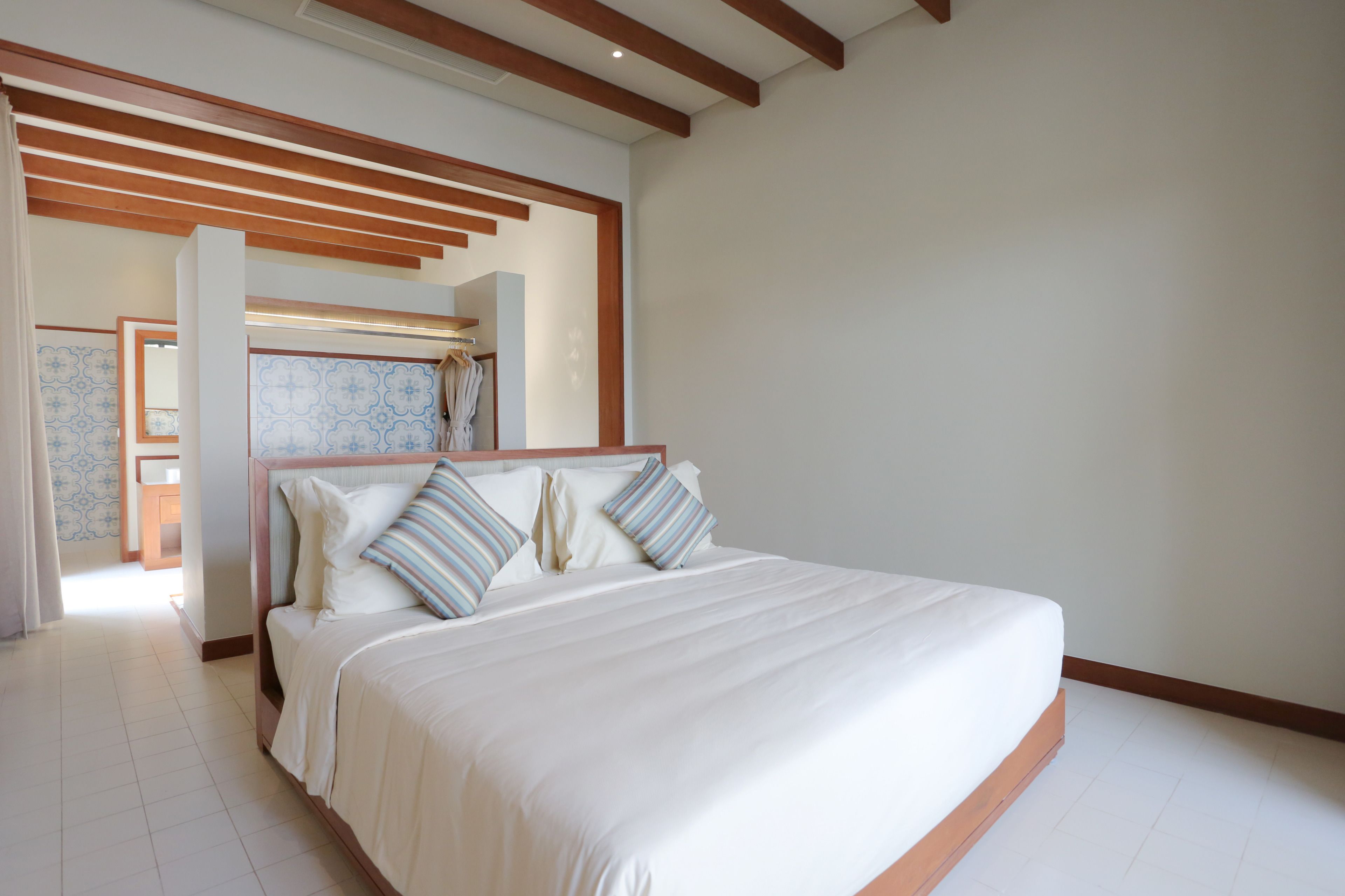 Un dormitorio con una cama grande, vigas de madera en el techo y vistas al baño.