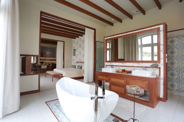 A modern bathroom with a freestanding bathtub, a large mirror, and a wooden vanity. - FLC Luxury Resort Samson (Sam Son)