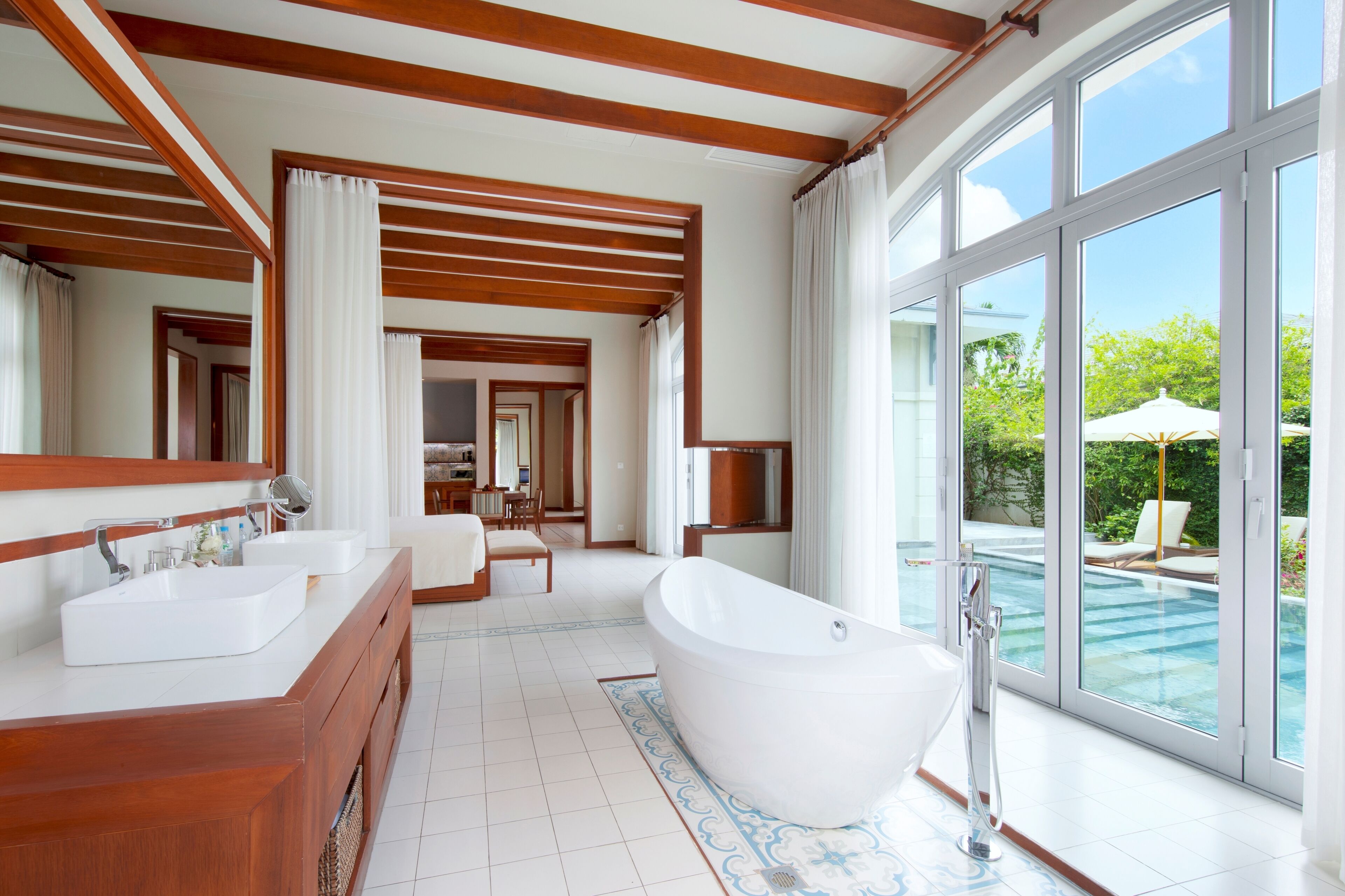 A spacious bathroom with a large bathtub, two sinks, and a glass-enclosed shower area.