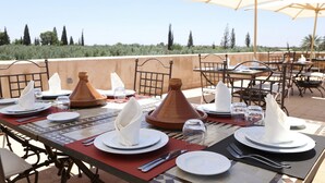 Un espacio de comedor al aire libre con mesas dispuestas para una comida, con vistas al campo.