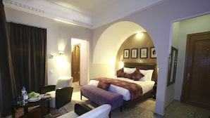 Habitación de hotel con cama, escritorio con silla, una mesita con un plato de comida y una puerta.