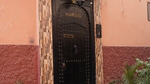 A black door with a decorative tile roof and a small lantern above it.