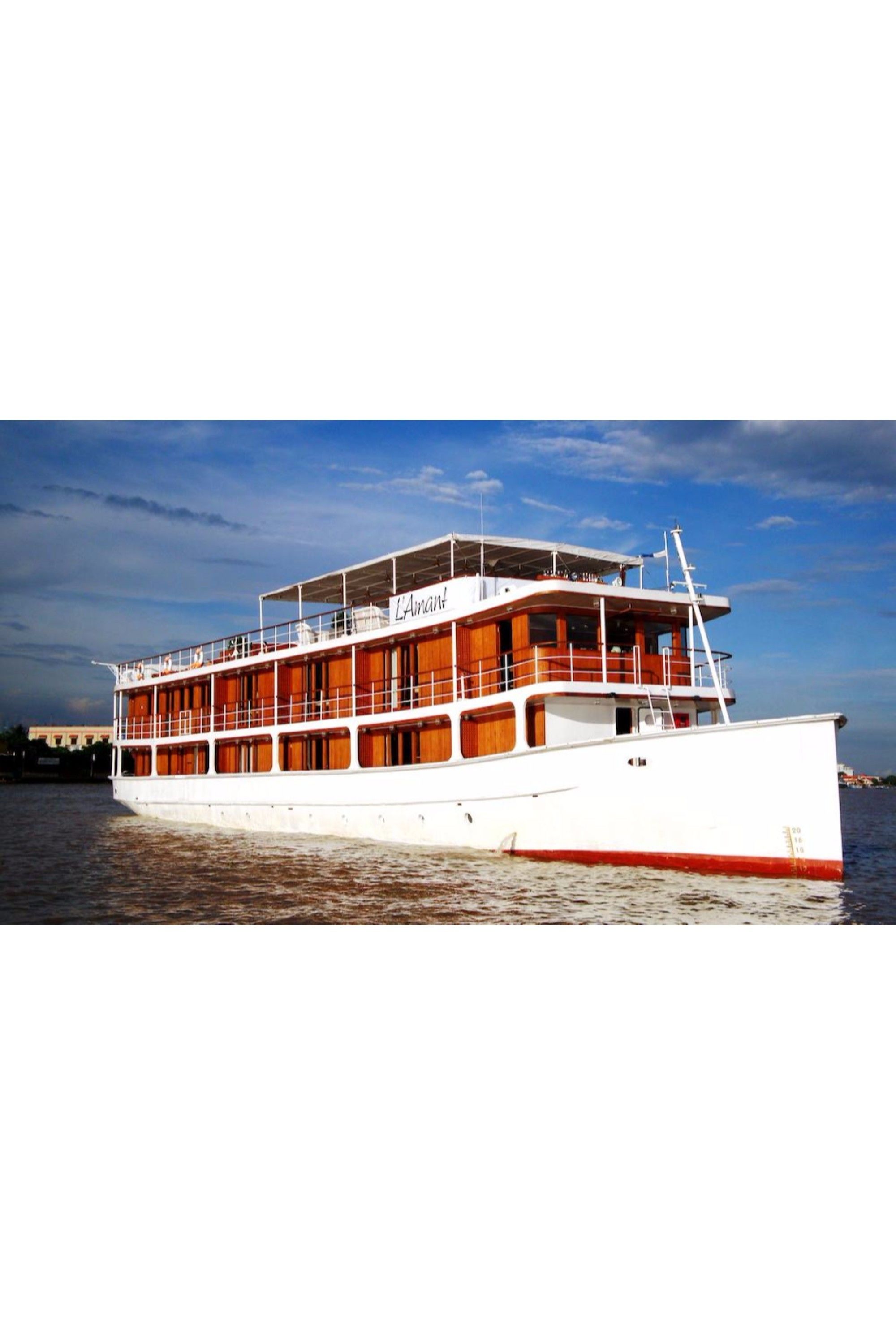 A large, multi-deck river cruise ship with a white hull and red trim, featuring multiple levels of wooden decks and enclosed seating areas.