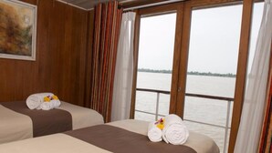 Two beds with towels, a painting, and a view of a body of water through large windows. - L'Amant Cruise (Thoi Son)