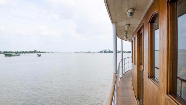 A wooden deck with a railing overlooking a calm river. - L'Amant Cruise (Thoi Son)