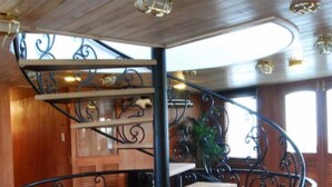 A spiral staircase with ornate black metal railings and wooden steps, leading to an upper level. - L'Amant Cruise (Thoi Son)