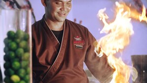 A chef performing a flambé with fire in a kitchen setting. - Aston Priority Simatupang Hotel & Conference Center (Jakarta)