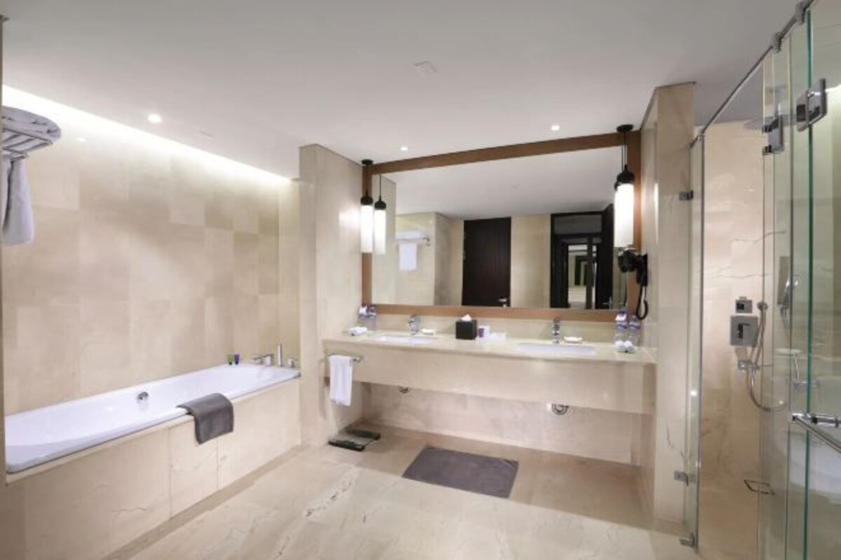 A modern bathroom with a bathtub, a large vanity with a mirror, and a glass shower enclosure.