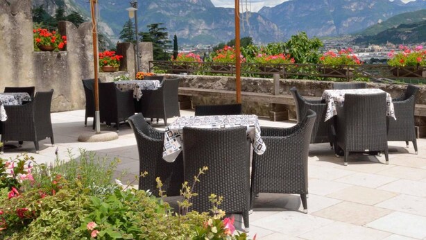 Un espace extérieur aménagé avec des chaises en osier et des parasols blancs, offrant une vue sur un paysage montagneux.
