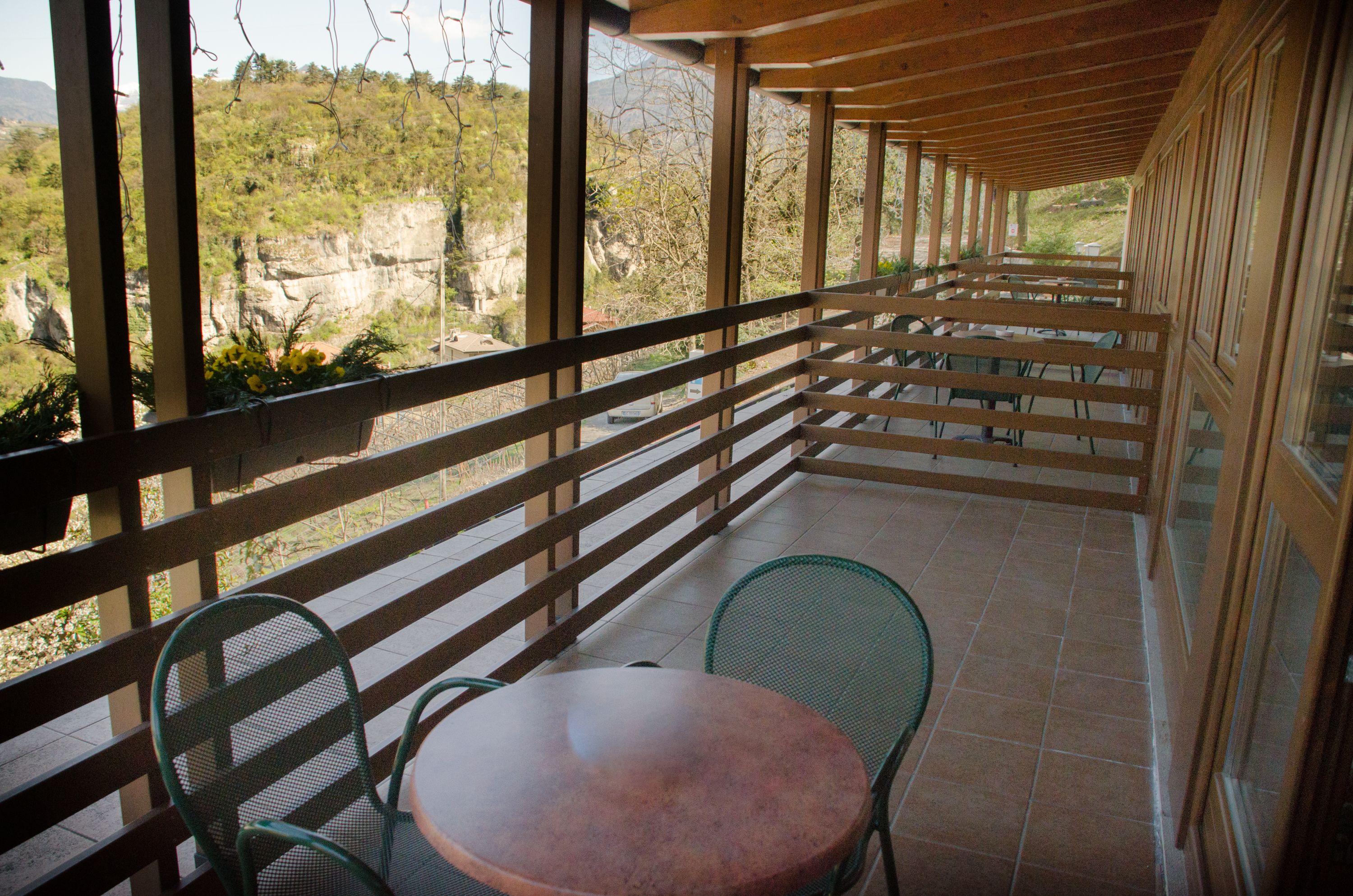 Un espacio de estar al aire libre techado con una mesa y sillas, con vistas a un paisaje montañoso.
