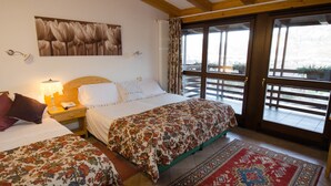 Une chambre à coucher avec un grand lit, un plus petit lit, une table de chevet, une lampe, un téléphone et une fenêtre donnant sur l’extérieur.