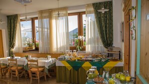 Un espace repas avec des tables préparées pour le petit-déjeuner, proposant une variété d’aliments et un buffet.