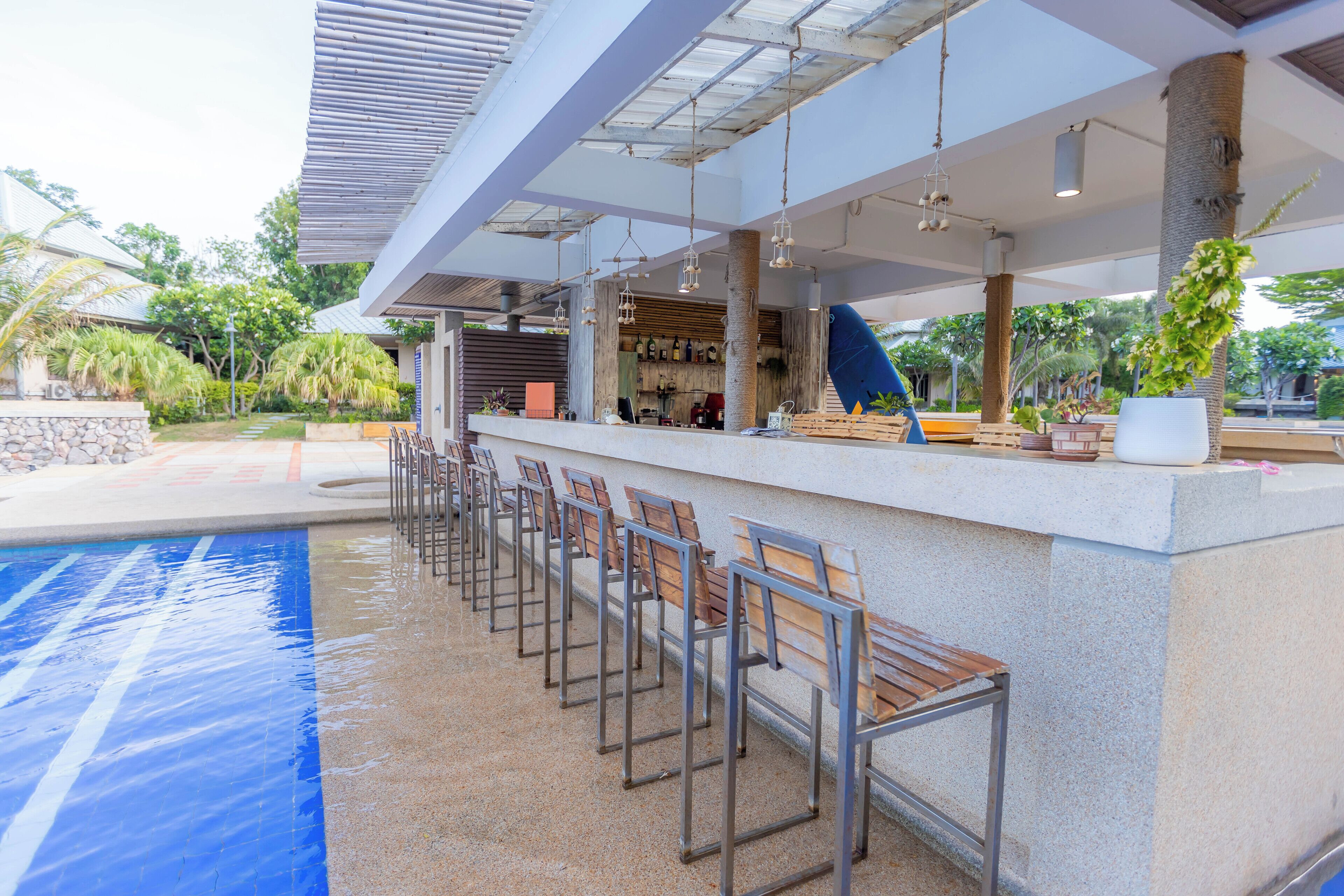 Zona de bar junto a la piscina, con sillas de metal y una barra.
