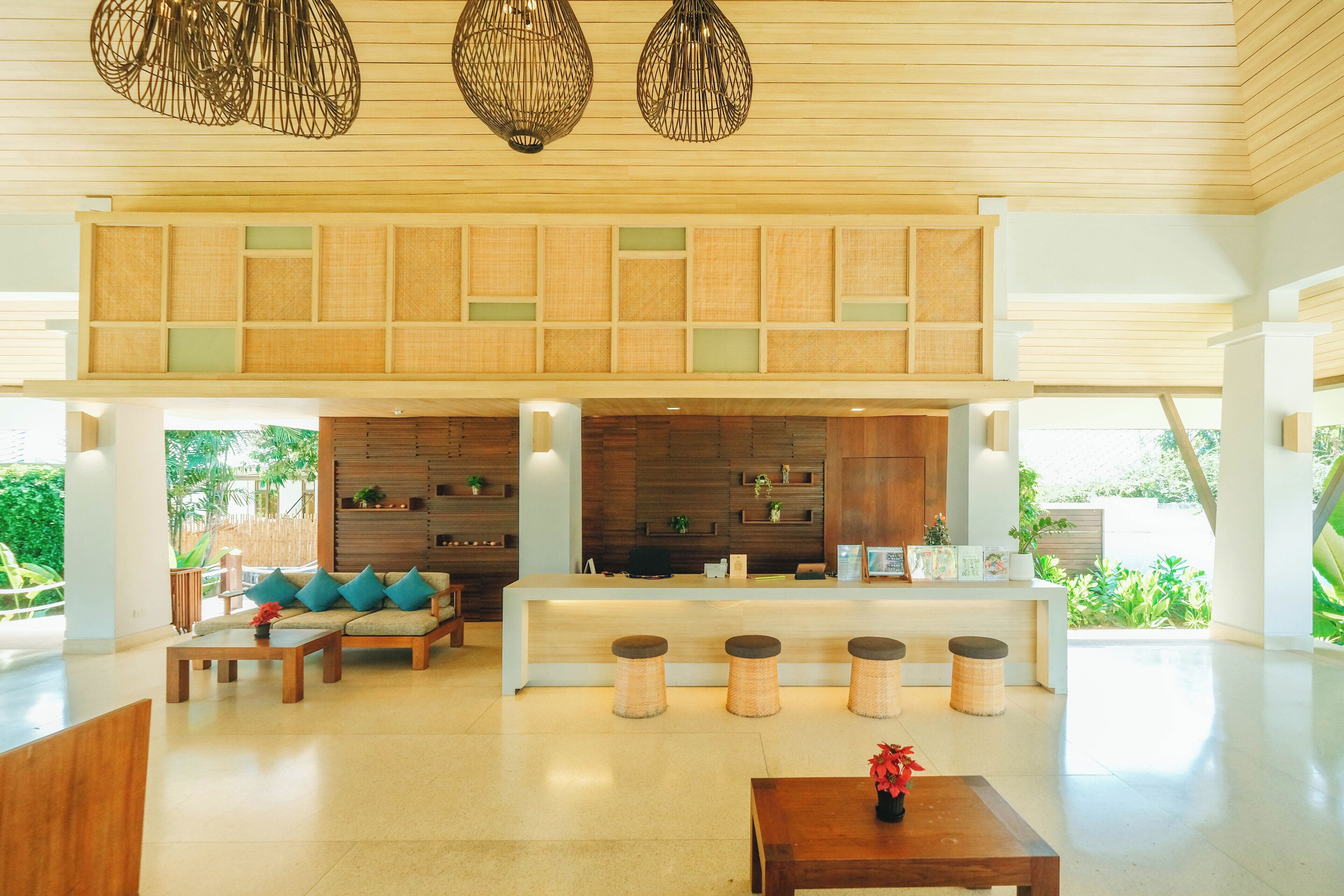 A spacious lobby with a reception desk, seating area, and a high ceiling with hanging light fixtures.