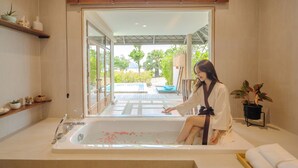 A woman sitting in a bathtub with a view of an outdoor deck and greenery. - Sirarun Resort (Thap Sakae)